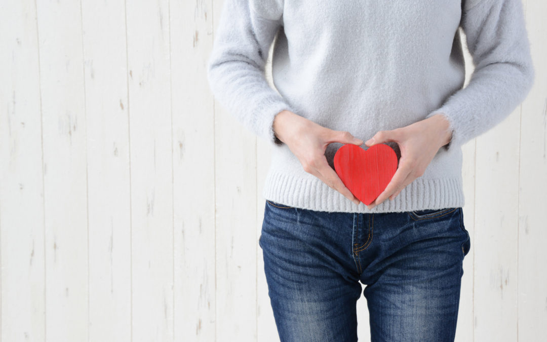 woman's waist with woman holding a red heart at her waist