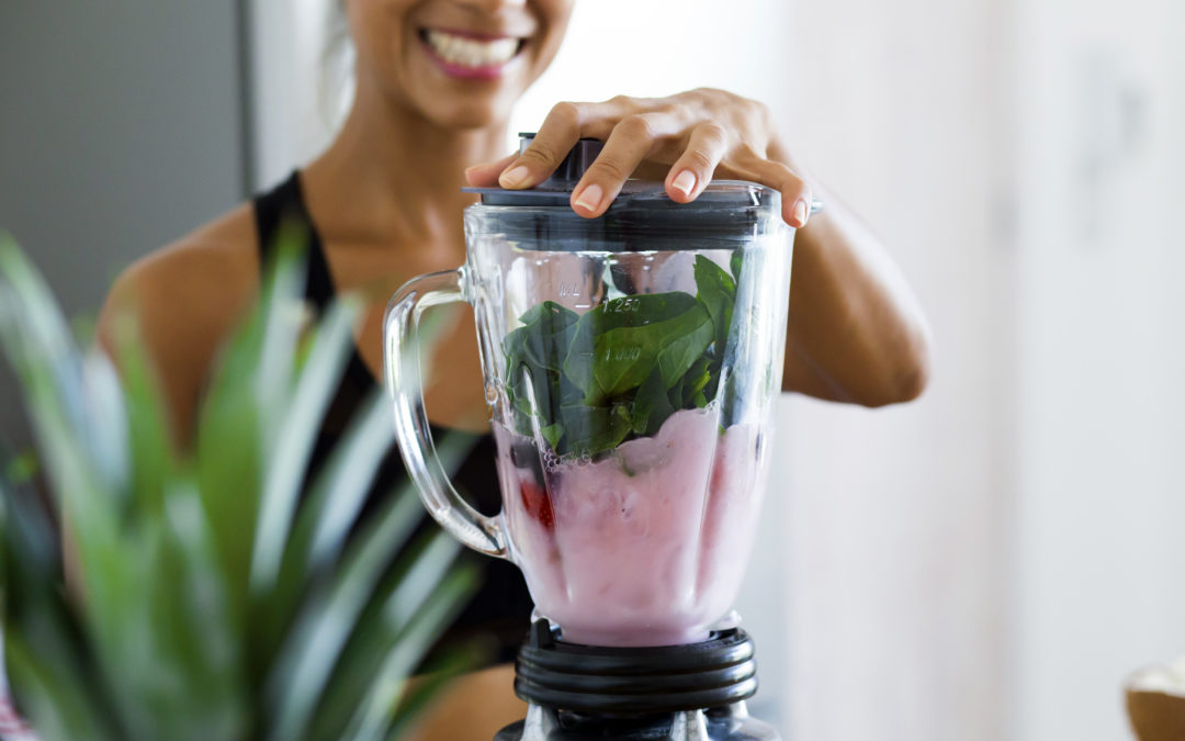 woman making a smoothie with spinach, berries and almond milk to help support a health immune system